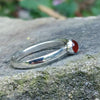 Sterling silver and orange carnelian stacking ring with 4mm round stone. Sitting on a rock
