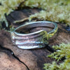 Slim Sterling silver melt top ring sits on a mossy log in th e sunshine.