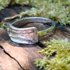 Slim Sterling silver melt top ring sits on a mossy log in th e sunshine.