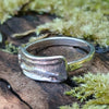 Slim Sterling silver melt top ring sits on a mossy log in th e sunshine.