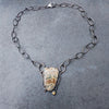 An oxidised sterling silver chain necklace with a shield-shaped natural edge ocean jasper pendant and a small round citrine stone, displayed on a slate surface.
