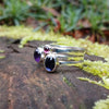 Silver 3 ring stacking set Amethyst oval Iolite oval and Garnet round. sitting on a mossy log