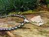 Raw Rose Quartz Pendant lying on a log