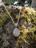 Seafoam seaglass pendant with  tendril details on thick spiga chain draped on a mossy log.