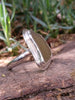 Large pale olive sea glass ring sitting resplendent on a mossy woodland log in the sunshine.
