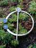 Traditional Silver brooch, penannular pin, ring pin with blue stones on a bed of green plants.