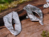 large molten textured Femscape stud earrings sitting on a mossy log in the sunshine.