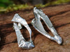 small molten textured Femscape stud earrings sitting on a mossy log in the sunshine.