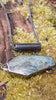 Oxidised silver pendant with coffin shaped  moss agate stone on a chunky chain. Sitting on a mossy log 