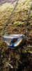 Oxidised silver half moon and chain necklace with tendrils. Sitting on a mossy log. 