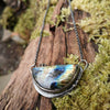 Oxidised silver half moon and chain necklace with tendrils. Sitting on a mossy log.