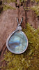 Oxidised silver pendant with a fat teardrop Labradorite stone sitting on a mossy log. back view