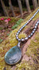 Oxidised silver pendant with a fat teardrop Labradorite stone on Black oval freshwater pearls sitting on a mossy log.