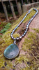 Oxidised silver pendant with a fat teardrop Labradorite stone on Black oval freshwater pearls sitting on a mossy log.