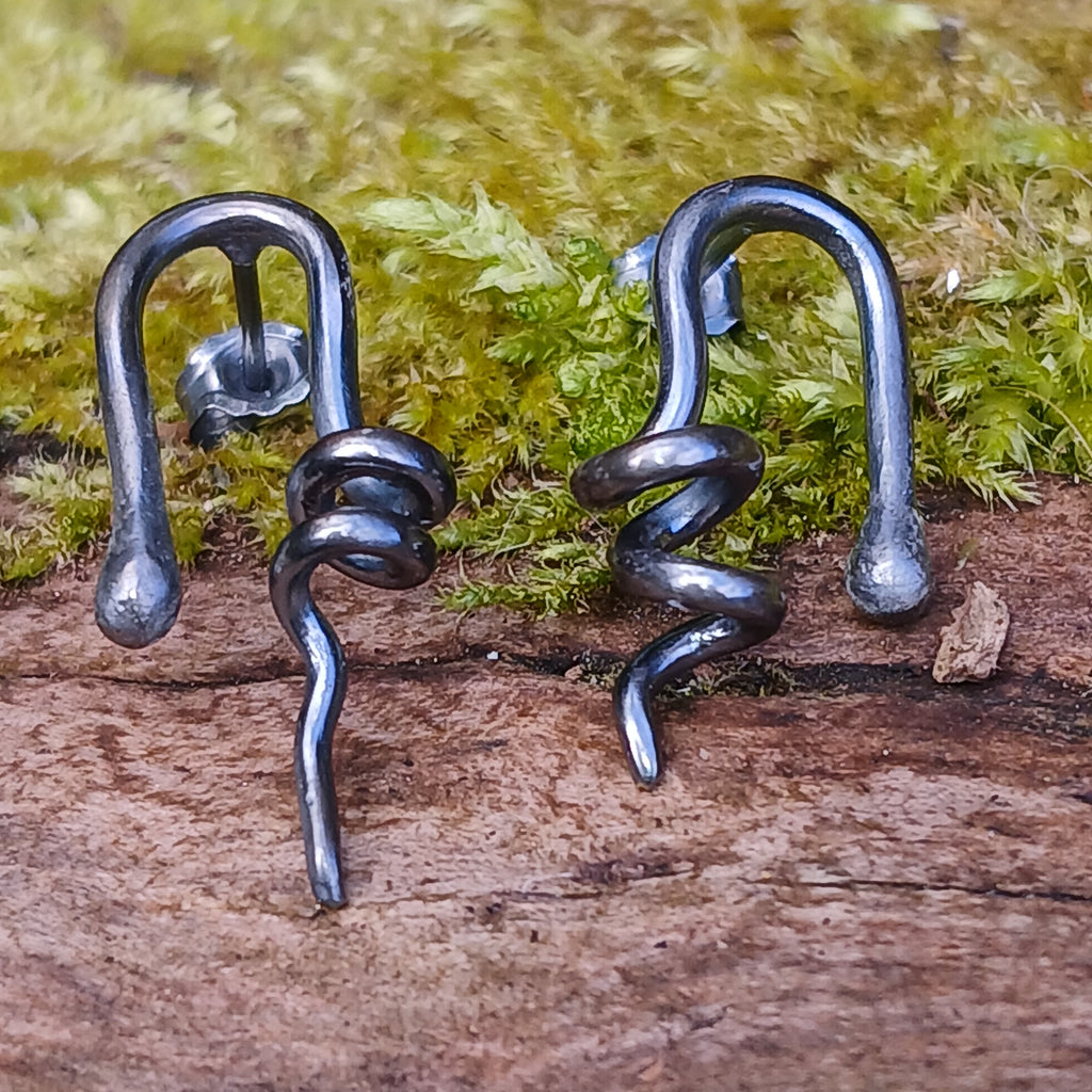 oxidised black Sterling silver twisted tendril studs sit on a mossy log
