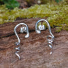 Sterling silver twisted tendril studs sit on a mossy log