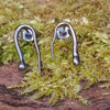 oxidised black Sterling silver twisted tendril studs sit on a mossy log