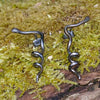 oxidised black Sterling silver twisted tendril studs sit on a mossy log