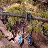 a pair of oxidised silver dangly earrings with leaf shaped blue flash labradorite on a mossy log