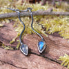 a pair of oxidised silver dangly earrings with bud shaped blue flash labradorite on a mossy log