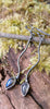 a pair of oxidised silver dangly earrings with bud shaped blue flash labradorite on a mossy log