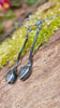 a pair of oxidised silver dangly earrings with bud shaped blue flash labradorite on a mossy log