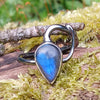 oxidised sterling silver tendril bud ring with blue flash labradorite on a mossy log.