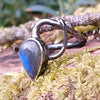 oxidised sterling silver tendril bud ring with blue flash labradorite on a mossy log.