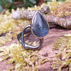 oxidised sterling silver tendril bud ring with blue flash labradorite on a mossy log.