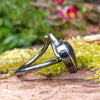 oxidised sterling silver tendril bud ring with blue flash labradorite on a mossy log.
