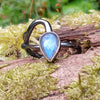 oxidised sterling silver tendril bud ring with blue flash labradorite on a mossy log.