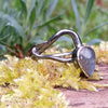 oxidised sterling silver tendril bud ring with blue flash labradorite on a mossy log.