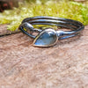 oxidised sterling silver twisted tendril bud ring with blue flash labradorite on a mossy log.