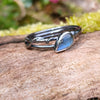 oxidised sterling silver twisted tendril bud ring with blue flash labradorite on a mossy log.