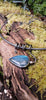 Oxidised black silver tendril pendant with blue flash labradorite bud winds around a bar and chain neckwire. Pictured on a mossy log