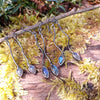 three pairs of oxidised silver dangly earrings with blue flash labradorite on a mossy log