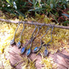 three pairs of oxidised silver dangly earrings with blue flash labradorite on a mossy log