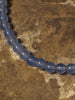 A necklace made of blue onyx beads on a slate background.